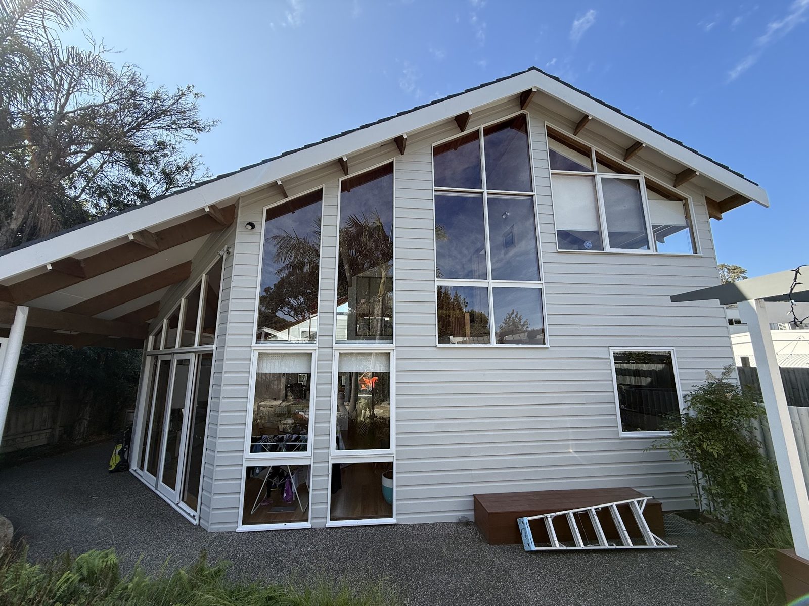 Two-storey weatherboard home in pale grey with white trims, ladder still on the lawn
