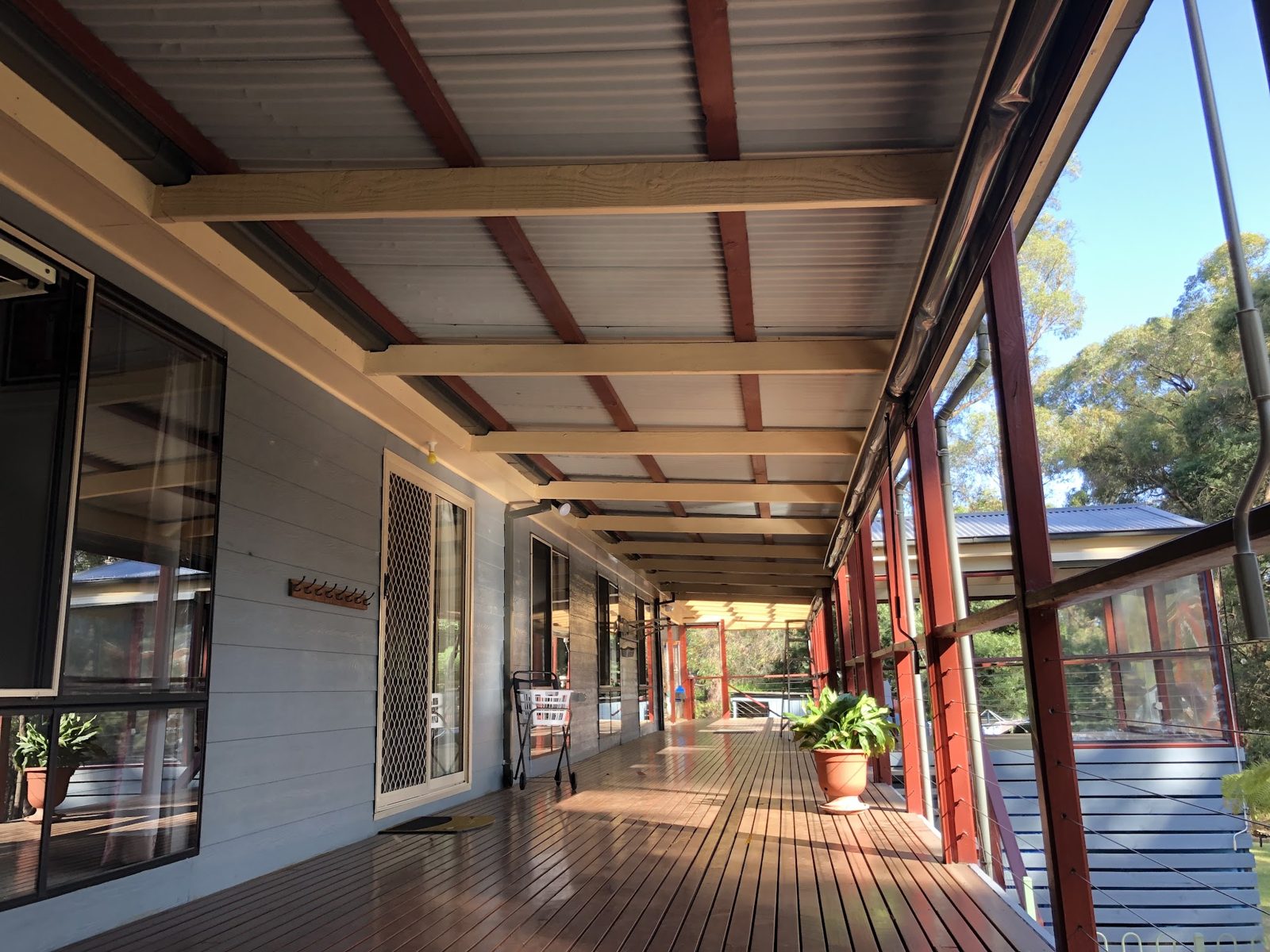 Long verandah with cream beams, blue-grey weatherboards and red posts