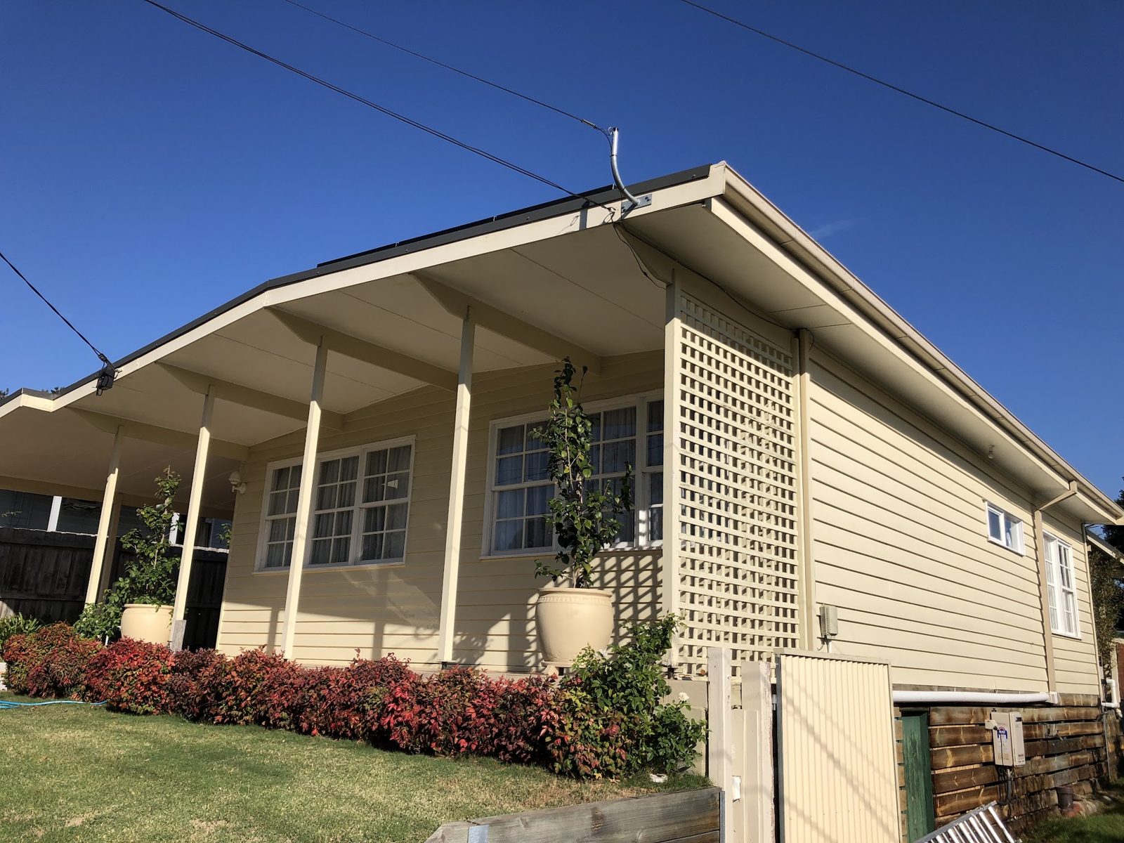 Cream weatherboard house with painted verandah posts and lattice